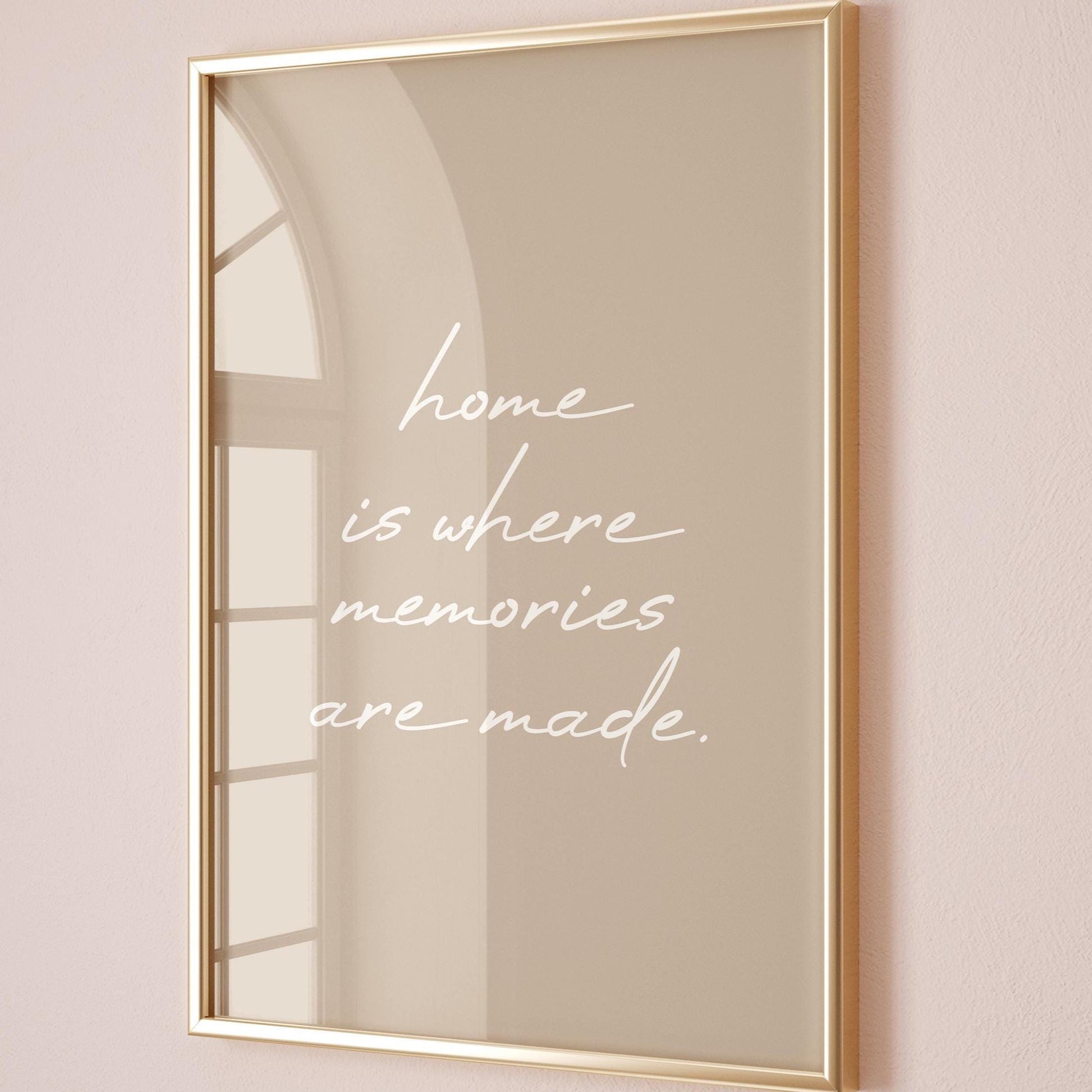 May include: A framed print with a gold-coloured frame. The print has a beige background with the white cursive text: "home is where memories are made."